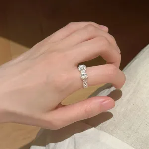 Nahaufnahme eines zarten filigranen Schleifenrings am Finger, elegantes offenes Design.