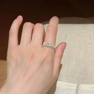 Nahaufnahme eines filigranen hohlen Silbermodeschmuckrings mit funkelndem Stein am Finger.