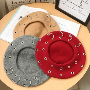Close up view of stylish punk wool berets with metal rings in various colors, detailed design.