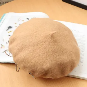 Detail view of a camel wool beret hat with punk metal rings, stylish retro autumn winter item.