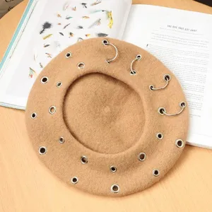 Detail view of the punk style wool beret featuring metal rings and grommets, close-up texture.
