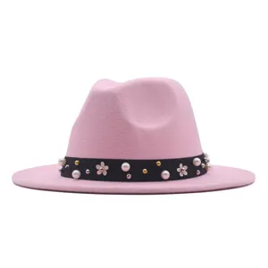 Nahaufnahme des rosa Fedora-Hutes mit einem schwarzen, perlenbesetzten Band und Blumen.