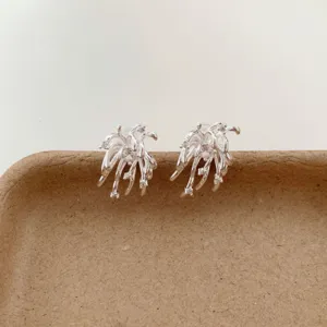 Primer plano detallado de pendientes de plata con diseño de fuegos artificiales y circonitas.