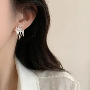 Pendientes de botón de fuego artificial plateados primer plano, joyas de oreja abstractas femeninas.