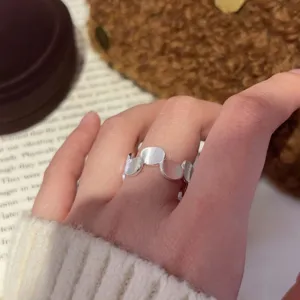 Close-up of a stylish geometric brushed silver open ring worn on a hand, trendy niche accessory.