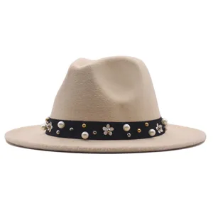 Nahaufnahme Detail des beige Fedora Hutes mit schwarzem Band, Perlen und Blumensteckern.