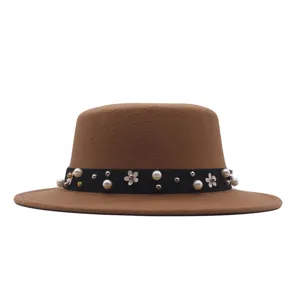 Detailed view of a chic camel flat-top wool hat featuring a black pearl flower decorated ribbon band.