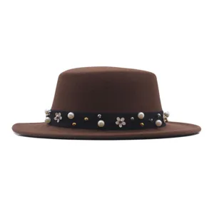 Brown flat top hat detail view, featuring elegant black ribbon with pearls and cute floral metal studs.