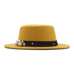 Detailansicht des eleganten gelben flachen Filzhutes mit schwarzem Band und Kunstperlen.