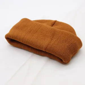Close-up shot of a brown knitted beanie, soft ribbed texture detail of winter hat.