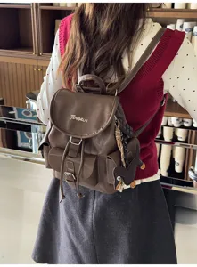 Detailed view of brown vintage leather backpack with multiple pockets and cute charm.