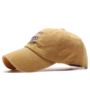 Vista detallada de la gorra de béisbol de algodón lavado amarillo con bordado de surf y textura fina.