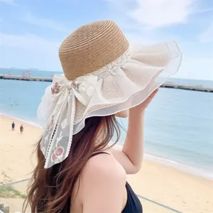 Cappello di paglia da donna con grandi volant, bordo in pizzo e fiocco floreale estivo.
