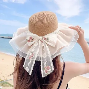 Vista dettagliata cappello di paglia donna con grande fiocco in pizzo e ricamo per la spiaggia.