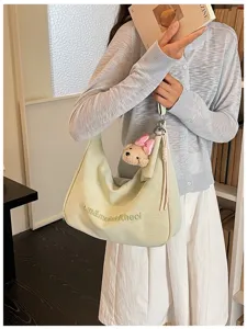 Detail shot of the pale green soft shoulder bag featuring cute embroidery and bear charm.
