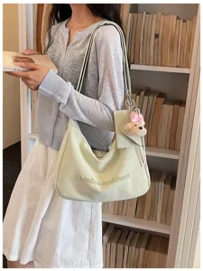 Detailed view of the light green hobo shoulder bag with cute teddy bear keychain and pouch.
