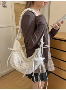 Chic white polka dot slouchy shoulder bag with cute bowknots and star pendant for women.