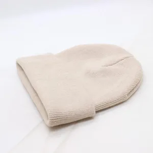 Close-up detail of a soft solid color knitted cuff beanie in a neutral beige tone for autumn.