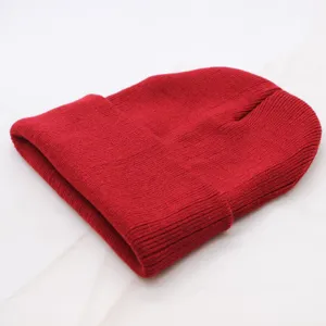 Red knit beanie detail shot, showing soft ribbed texture and cozy winter folded cuff design.