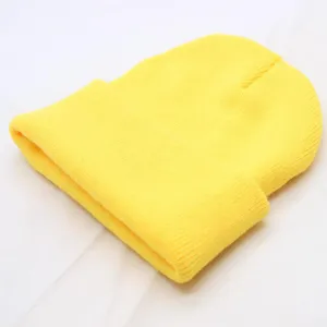 Close-up detail of a bright yellow knitted beanie hat, solid color winter warm woolen cap.