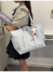 Light blue tote bag detail showcasing star and moon print, side pockets and cute star pendant.