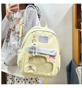 Cute light yellow student backpack detail with transparent window and fluffy doll charm.