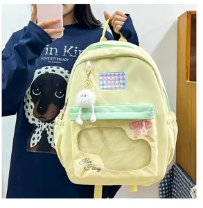 Detailed view of light yellow backpack with clear front window, furry pendant and embroidery.