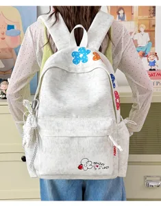 Backpack detail view featuring cute floral print, front pocket design and stylish ribbon pendant.
