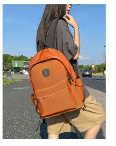 Detailed view of stylish orange nylon backpack worn outdoors by model, minimalist daily wear.