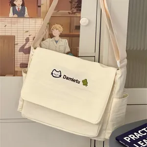Detailed view of the cute canvas messenger bag in cream white with cat embroidery and straps.