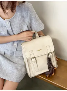 Detail shot of a versatile cream vintage-style rucksack with dual straps and charming pendant.