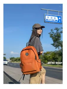 Detail view of stylish orange nylon student backpack with circular logo badge outdoor setting