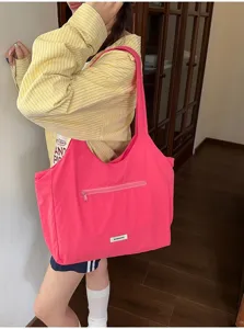 Gedetailleerd overzicht van de levendige roze canvas tas met voorzak met rits en handvatten.