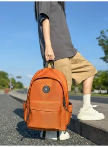 Orange nylon student backpack, minimalist style school bag, detail carrying view.