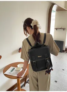 Detailed view of the stylish black backpack worn by a model in a cafe setting, showing its design.