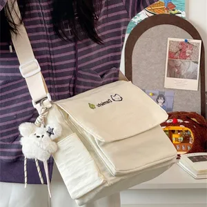 Japanese ins style canvas messenger bag detail view with cute plush bear pendant and front pocket.