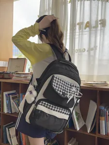 Detail view of the student backpack showcasing multi-pocket design and cute plush pendant.
