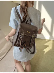 Vintage brown leather backpack detail showcasing flap buckle strap design and cute pendant.