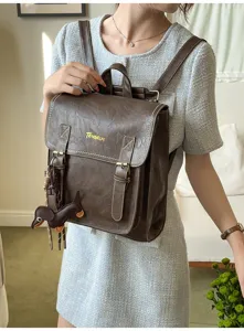 Detail view of retro PU leather backpack with cute dog charm and metallic buckle accents.