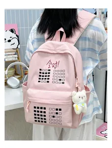 Pink canvas student backpack detail with grid pattern and cute plush bear charm.