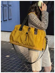Detailed view of the yellow travel duffel bag with black straps, showcasing functional design.