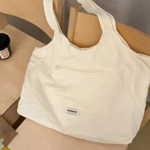 Casual minimalistische nylon tote tas in off-white met voorvak met rits en comfortabele riemen.