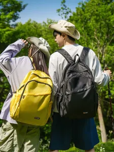 Detailed outdoor view of lightweight hiking backpacks worn by active couple in nature setting.