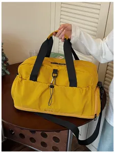 Detailed view of the yellow travel duffel bag showing durable black straps, front pocket design.