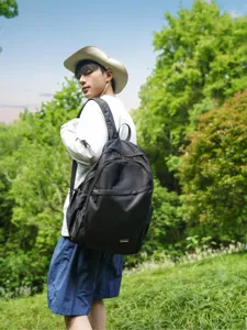 Detailed view of the lightweight outdoor backpack worn by a model in a natural forest setting.