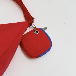 Red nylon crossbody shoulder bag detail featuring a cute matching detachable mini pouch.