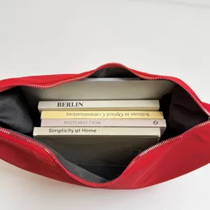 Red canvas shoulder bag interior detail showing book storage capacity and zipper design.