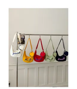 Canvas shoulder bag with colorful embroidered letters and small coin purse pendant for daily wear.