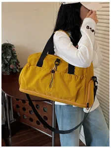 Detail view of large capacity yellow travel duffel bag with black straps and side zipper pocket.