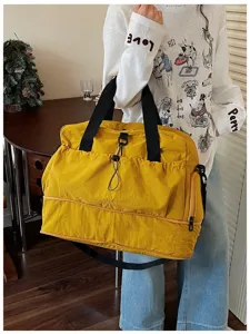 Detail shot of yellow travel duffel bag with black straps and wet dry separation pocket.
